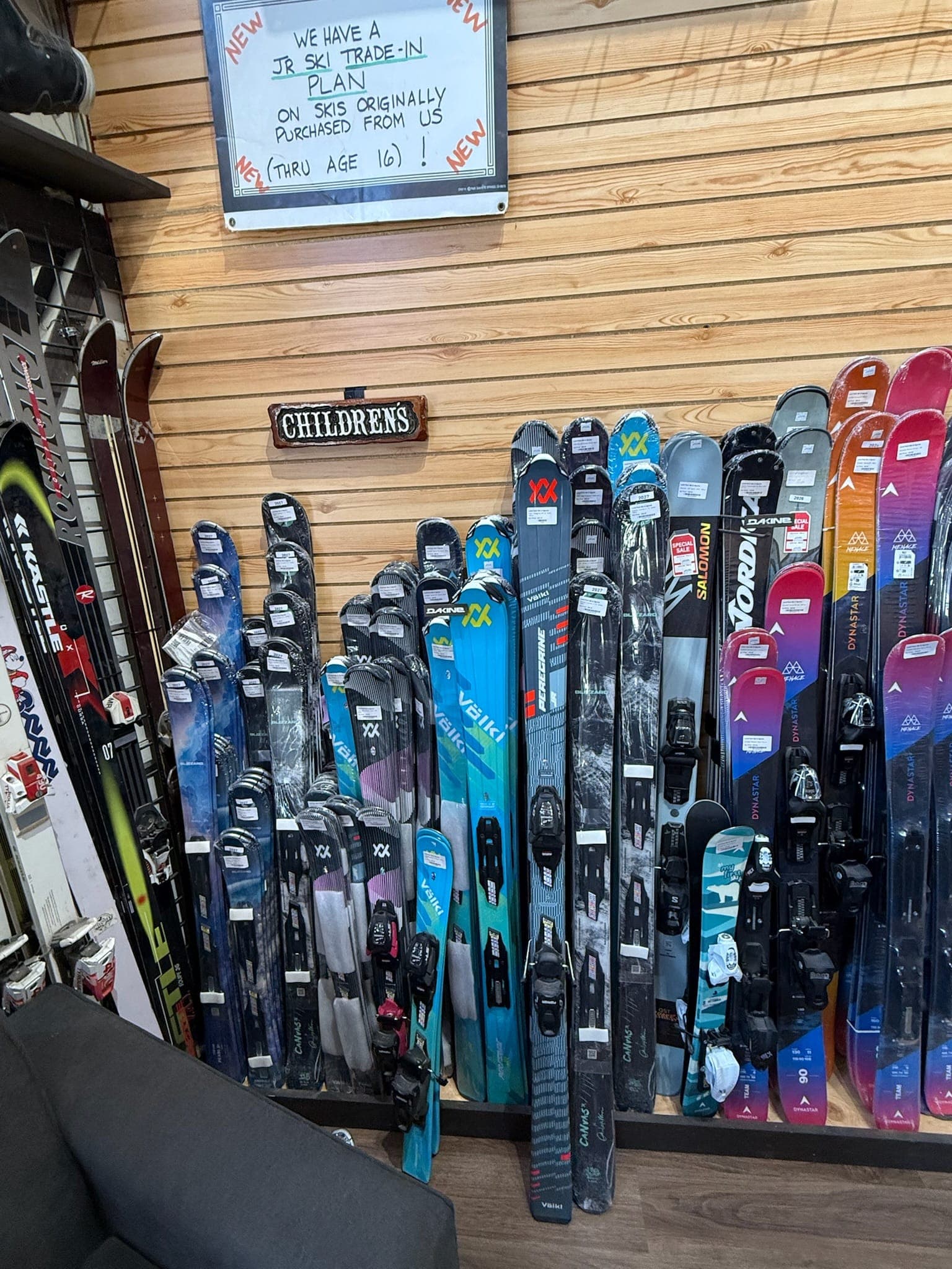 The children's corner stocked with junior skis, with the trade-in board on the wall